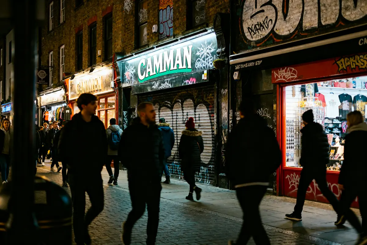 Personnes marchant sur un trottoir graffité à Camden Town réputé dangereux le soir.
